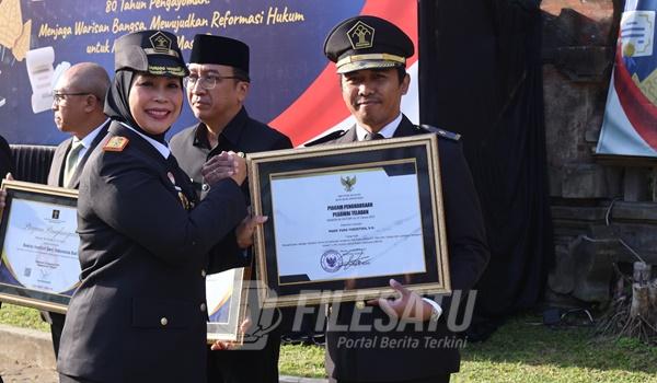 Made Yuda Yudistira menerima penghargaan dari Kepala Kanwil Kemenhum Bali