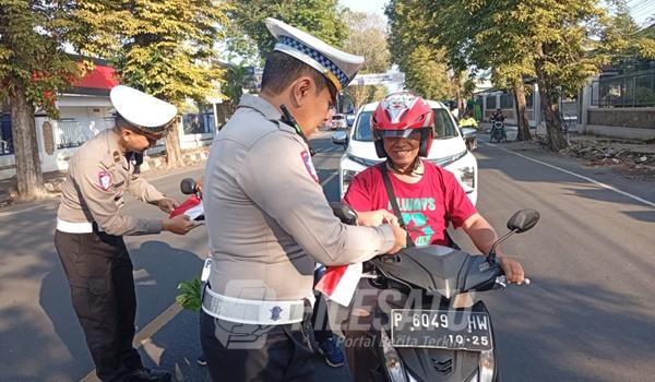 Petugas Satlantas Polres Jember saat pasangkan Bendera Merah Putih pada penegdara motor