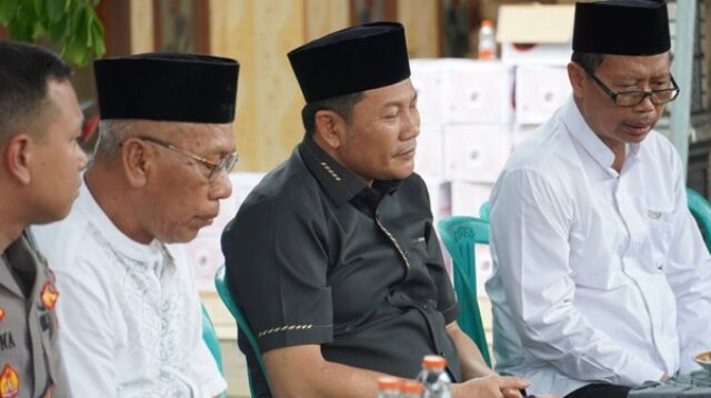 Bupati Sidoarjo H. Subandi mengenakan kemeja hitam dan peci, duduk takziah di rumah duka praja IPDN dengan ekspresi berduka, didampingi jajaran pejabat dan aparat
